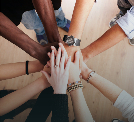 Mehrere Personen stehen im Kreis und legen ihre Hände übereinander